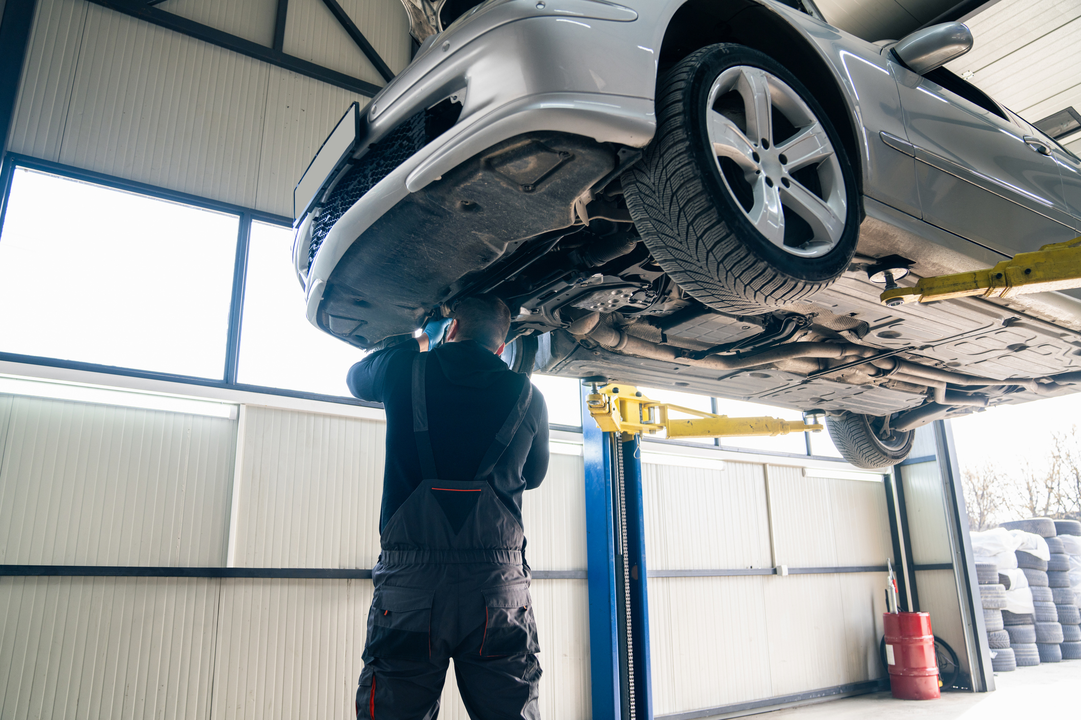 Technician inspecting the underside of a vehicle on a lift at HiWay Auto Collision Center