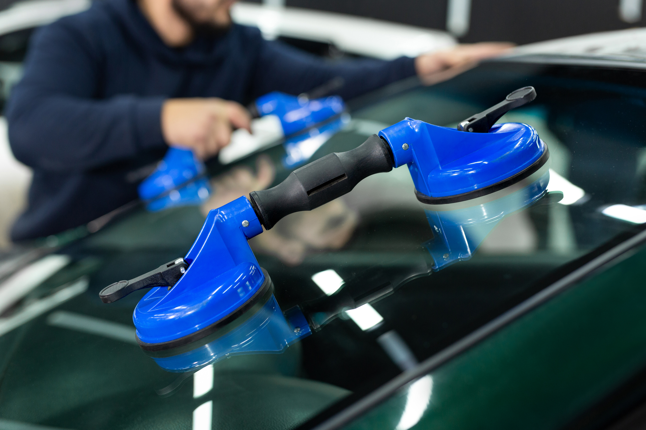 Technicians using glass-handling tools to set a windshield at HiWay Auto Collision Center